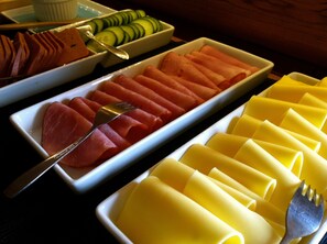A buffet with various food items including sliced ham, cucumbers, and pasta. - Försgården Bed & Breakfast (Transtrand)