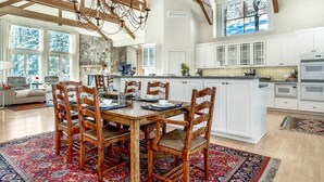 A spacious kitchen with white cabinets, a large island, and a stone accent wall.