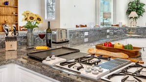 A modern kitchen with a granite countertop, a built-in toaster, a gas stove, and a variety of kitchen utensils.
