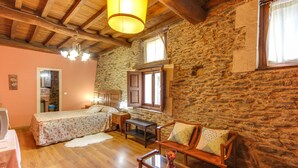 Ein gemütliches Zimmer mit zwei Betten, einem Holzsofa, einem kleinen Tisch und einer Steinwand.