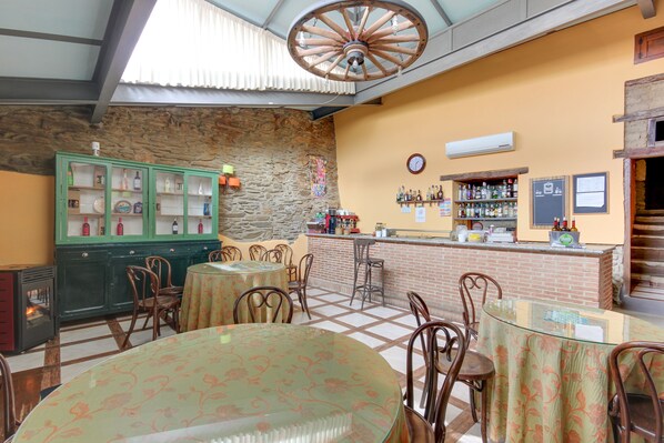Un restaurante con pared de piedra, sillas de madera, un armario verde y una zona de bar.
