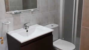 A bathroom with a white sink, dark cabinet, and a toilet. - Miramar Habitaciones (Aguilas)
