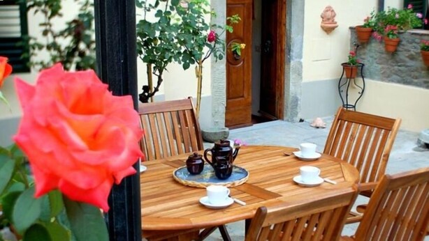Una mesa de madera con sillas, un juego de café y una planta en maceta.