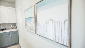 A kitchen with grey cabinets, a countertop with kitchenware, and two framed beach paintings on the wall. - ❀Aloha❀ - Tropical Island Retreat | POOL IS OPEN!!! Great Family Friendly Vacation! (Washington)