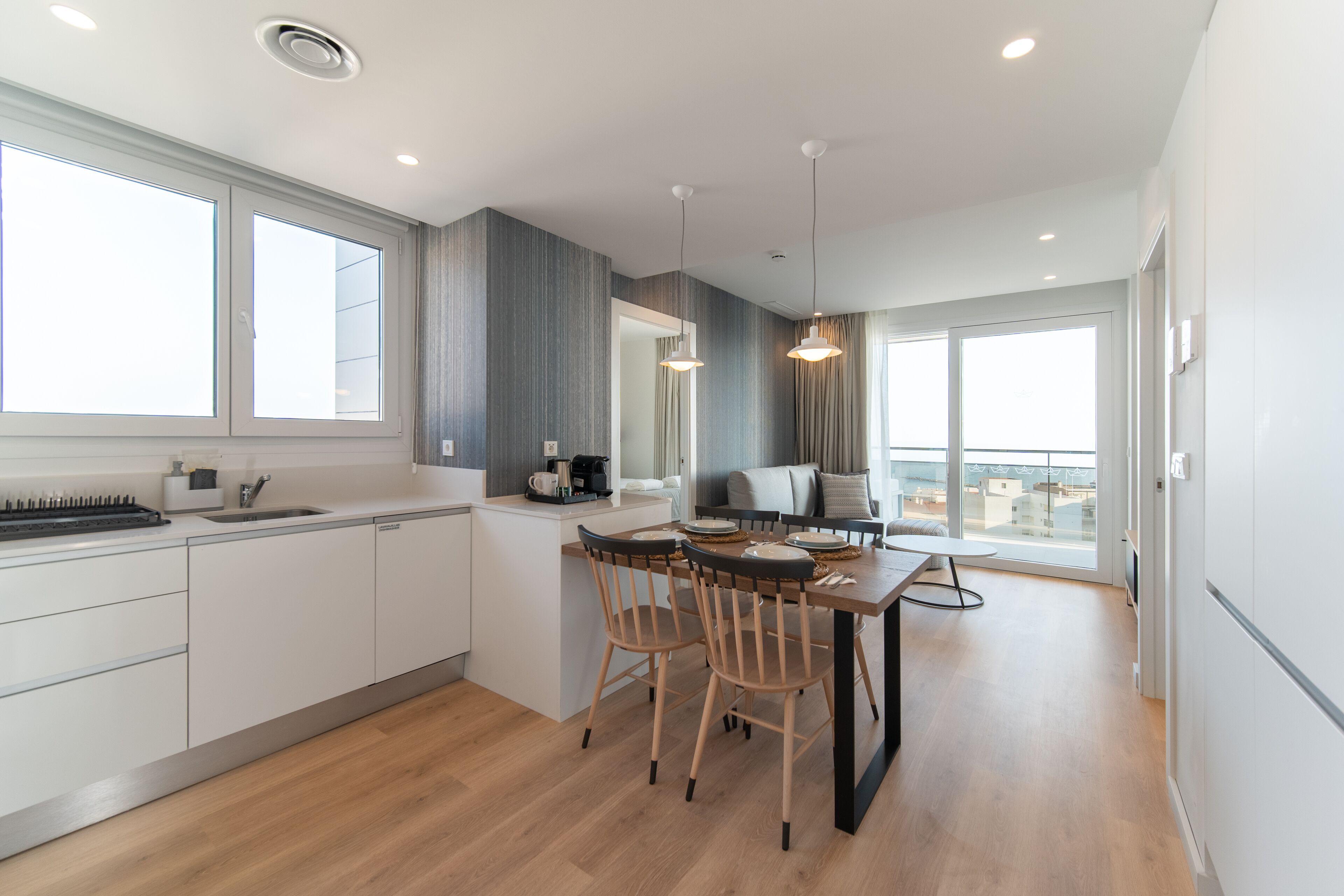 A modern kitchen with a dining area, large windows, and a view of the city.