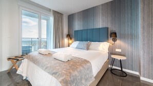A modern hotel room with a large bed, a view of the city, and a balcony. - Ahoy Apartments (El Campello)
