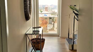 Un pasillo con vista al exterior, una cesta y una planta.
