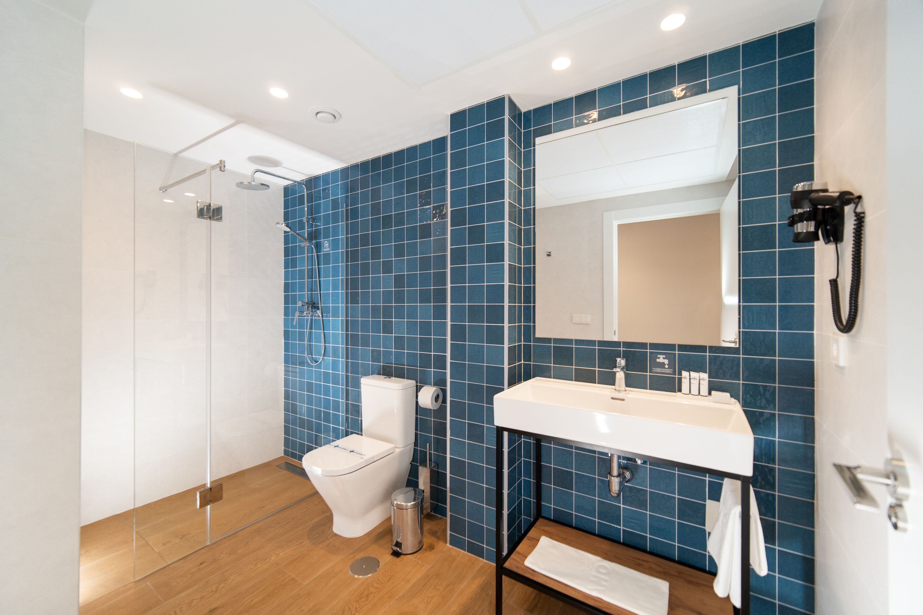 A modern bathroom with a glass shower enclosure, a white toilet, and a sink with a mirror above it.