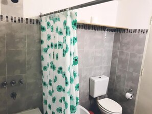 A bathroom with a shower curtain, a toilet, and a hand dryer. - Hostel Casa Borges (Adrogué)