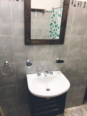 A bathroom with a white sink, a mirror, and a shower curtain.