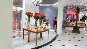 Um hall moderno com um balcão de recepção de madeira, um candelabro e um padrão de piso colorido.