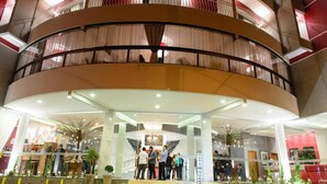 Entrada de hotel com fachada curva, várias varandas e uma escadaria central que leva ao saguão.