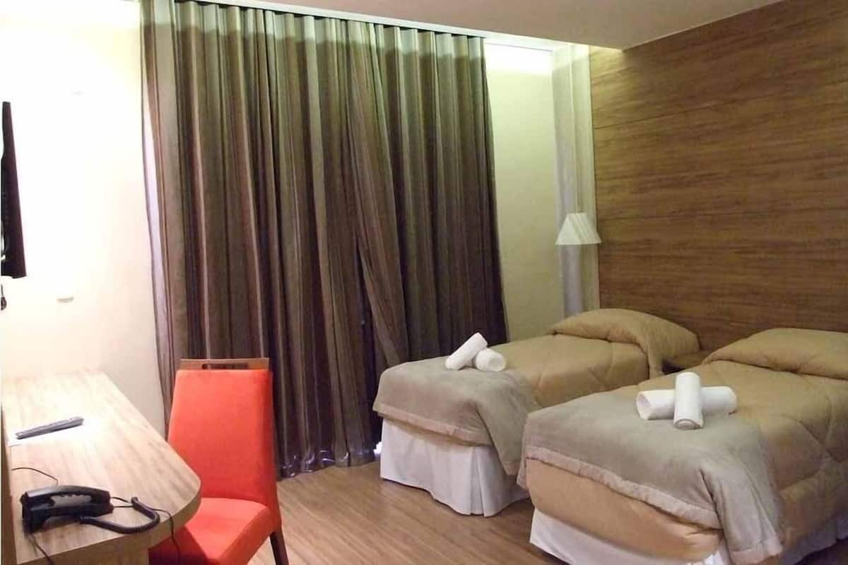A hotel room with two beds, a desk with a telephone, and a chair.