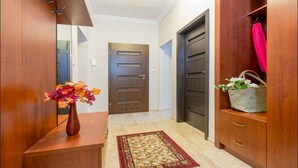 A hallway with wooden doors, a vase with flowers, and a woven basket. - P&O Apartments Freta 2 (Warsaw)