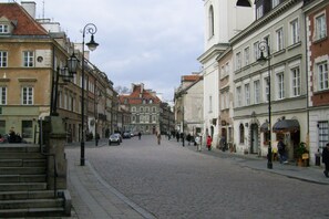 A cobblestone street lined with historic buildings, featuring a mix of architectural styles and a few pedestrians. - P&O Apartments Freta 2 (Warsaw)