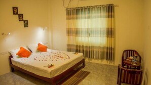 A bedroom with a bed, a chair, a curtain, and wall-mounted lights. - Golden Queen Guest House (Ngapali)