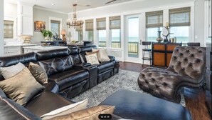 Ein geräumiges Wohnzimmer mit einer großen schwarzen Ledersofa, einem gepolsterten Sessel und einem Essbereich mit einer Bar.