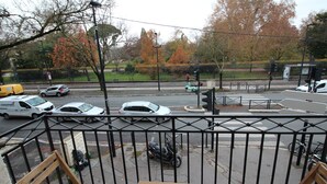 Ein Balkon mit Holzmöbeln, der auf eine Straße mit Autos und einer Ampel blickt.