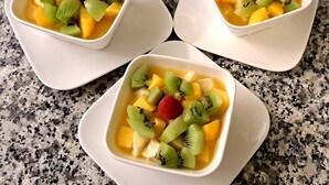 Tre ciotole bianche quadrate con frutta su un piano di lavoro in granito.