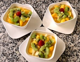 Tres cuencos blancos cuadrados con fruta sobre una encimera de granito.