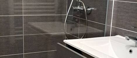 A modern bathroom with a bathtub, a sink, and a shower.