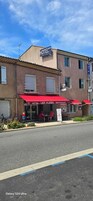 Un hotel con toldo rojo y un cartel que dice "HOTEL LES ALIZES RESTAURANT".