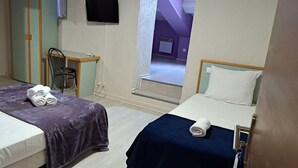 Una camera d'albergo con due letti, una scrivania, una sedia e un televisore.