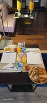 Una mesa en una habitación de hotel con desayuno: cereales, fruta, jugo y pasteles.