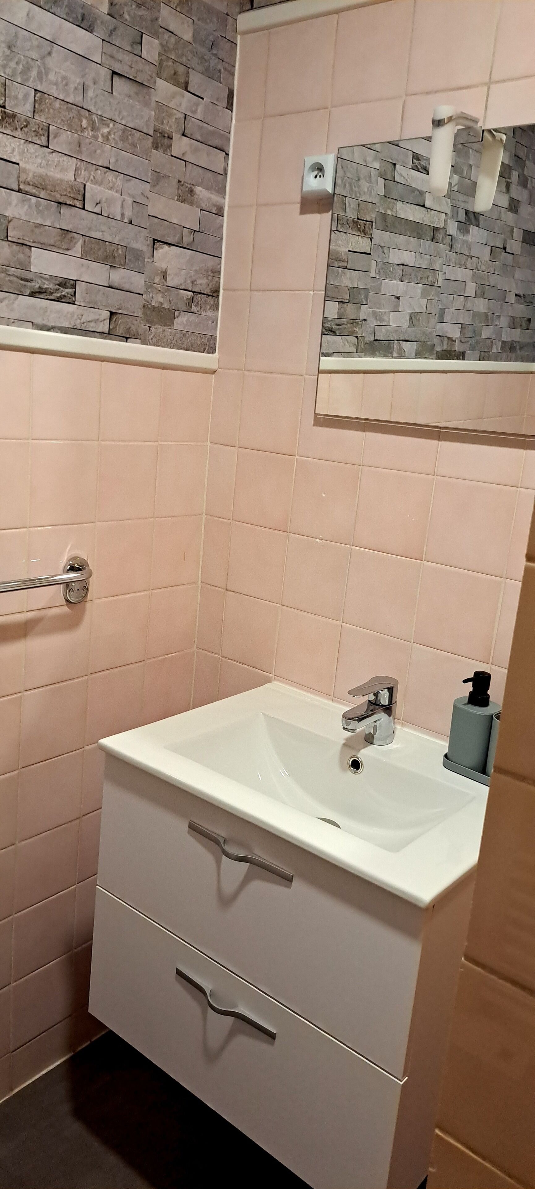 A bathroom with a white sink, a mirror, and a tiled wall.