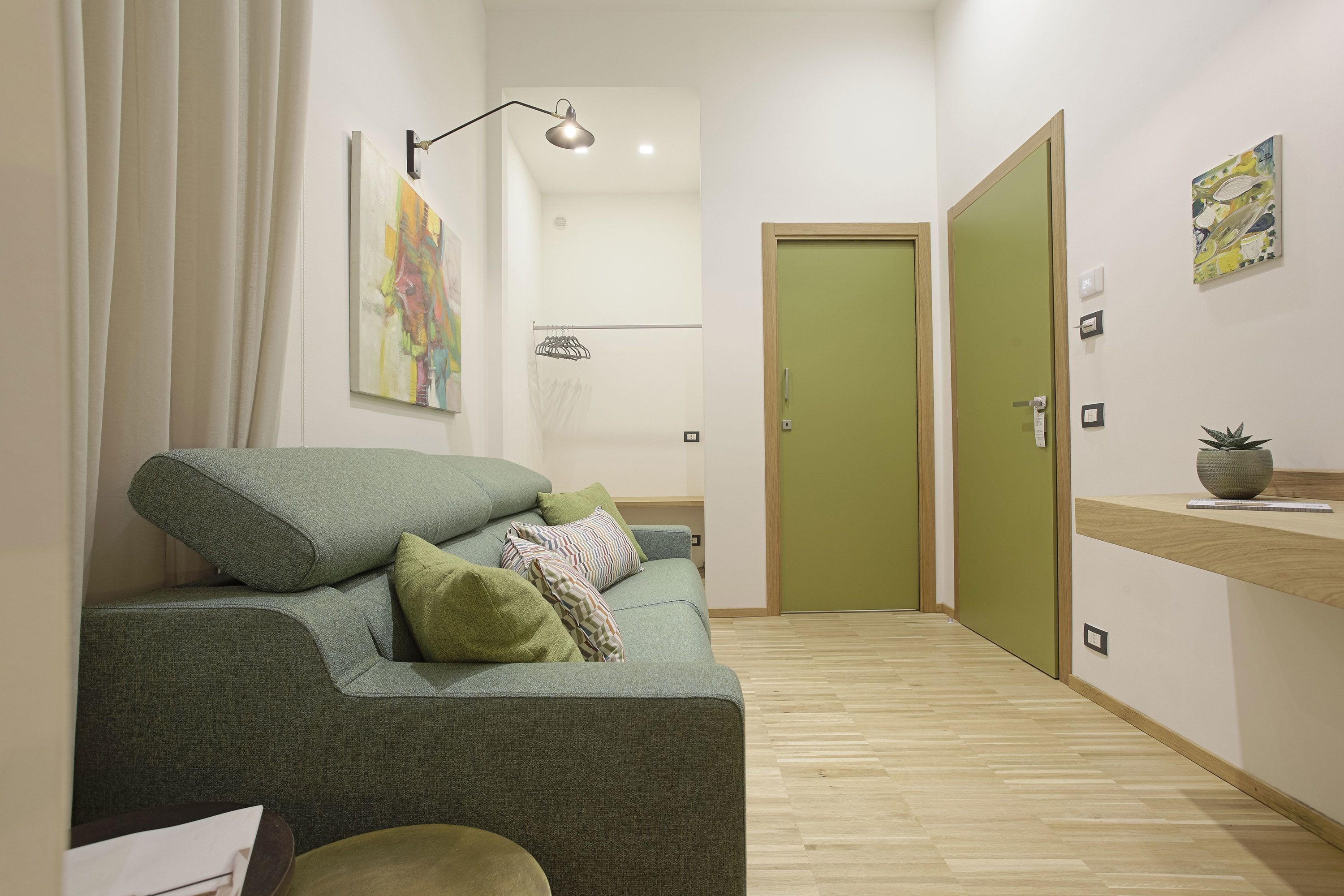 A modern living room with a green sofa, a small table, and a green door.