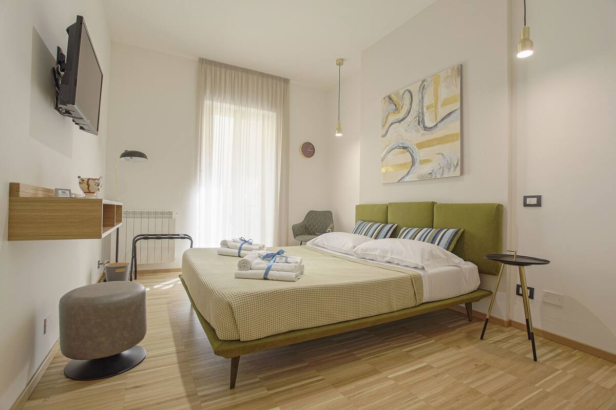 Un dormitorio moderno con cama, mesita de noche y una obra de arte en la pared.