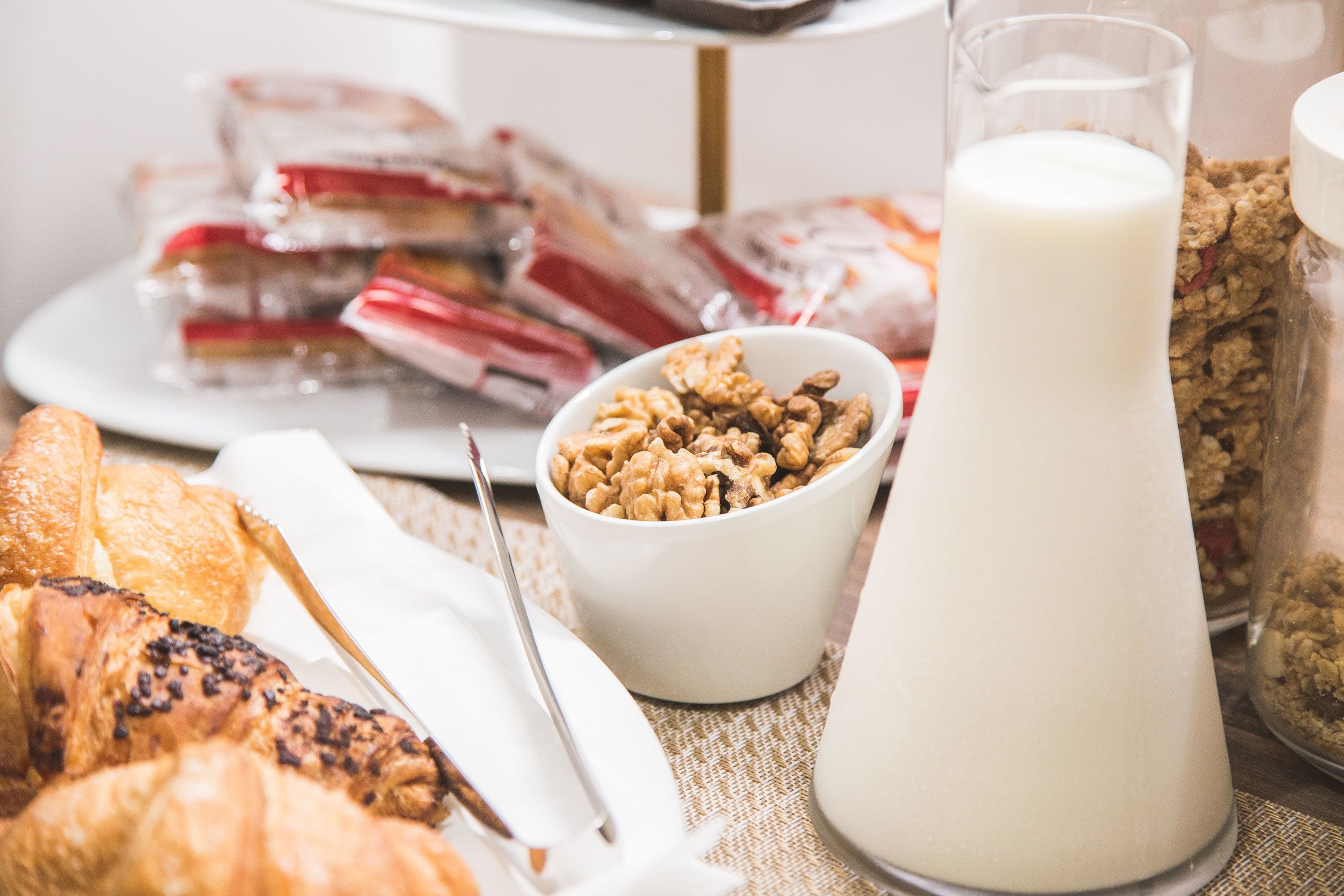 Un desayuno con pasteles, un vaso de leche y un tazón de nueces.