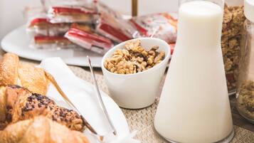 Un desayuno con pasteles, un vaso de leche y un tazón de nueces.