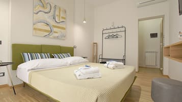 A modern bedroom with a green headboard, a large abstract painting, a bed with white linens, and a bedside table.