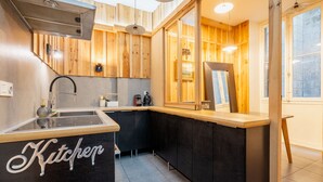 Una cocina moderna con detalles de madera, salpicadero de vidrio y encimera negra con la palabra 'Kitchen'.