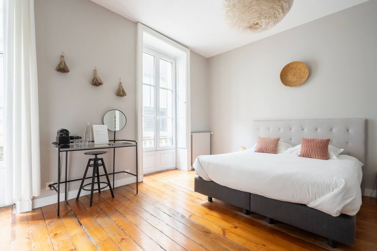 A bedroom with a bed, a desk with a chair, a window, and a ceiling light.