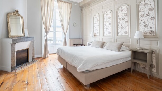 Un dormitorio con una cama grande, una chimenea y paneles decorativos en las ventanas.