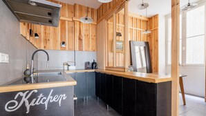 Una cocina moderna con paneles de madera, encimera negra y pileta de acero inoxidable.
