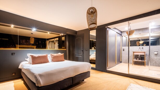 Un dormitorio moderno con una cama grande, cabina de ducha de vidrio y baño a la vista.