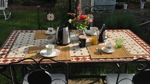 Taula preparada per esmorzar amb cafè, te i suc, amb cadires al voltant.