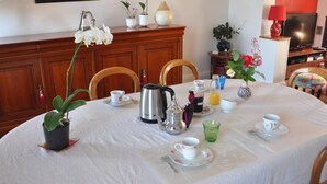 Taula de menjador preparada amb tasses de te, tetera, cafetera i un ram de flors.