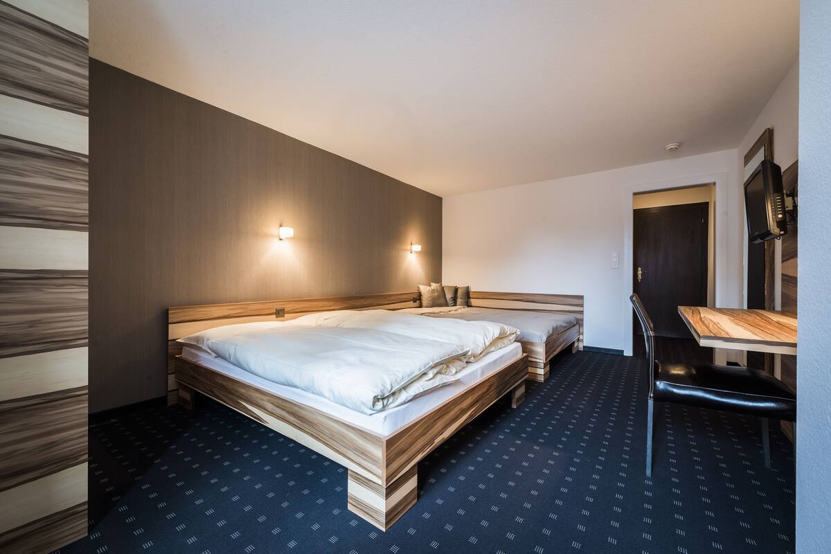 Ein Hotelzimmer mit zwei Betten, einem Schreibtisch und einem Stuhl.