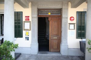 L’entrée d’un immeuble avec une enseigne indiquant : « Restaurant, hôtel, bistro ».