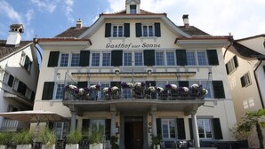 A building with a balcony adorned with flowers, a sign reading "Gasthof zur Sonne," and a classic architectural style. - Gasthof zur Sonne (Stafa)
