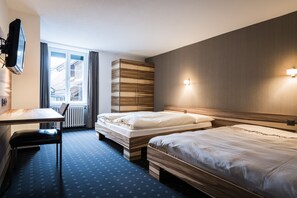 Une chambre d’hôtel avec deux lits, un bureau, une chaise, une télévision et une fenêtre avec des rideaux.