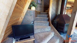 A wooden staircase with a television on a stand at the bottom. - Classic Cabin | Fireplace | Skyview 'A' Frame of Mind (Angel Fire)