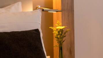 A bed with white and dark pillows, a wooden headboard, and a bedside table with a lamp.