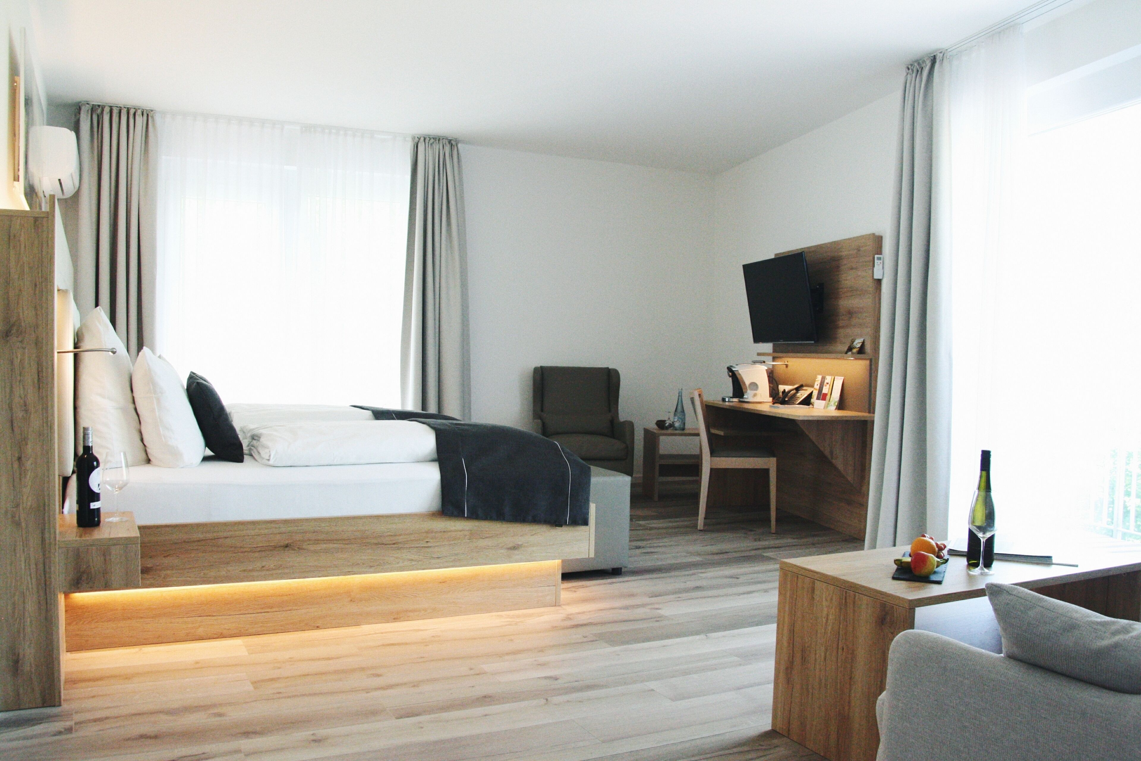 Ein modernes Hotelzimmer mit Bett, Schreibtisch, Fernseher und einer Sitzecke.