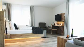 Ein modernes Hotelzimmer mit Bett, Schreibtisch, Fernseher und einer Sitzecke.