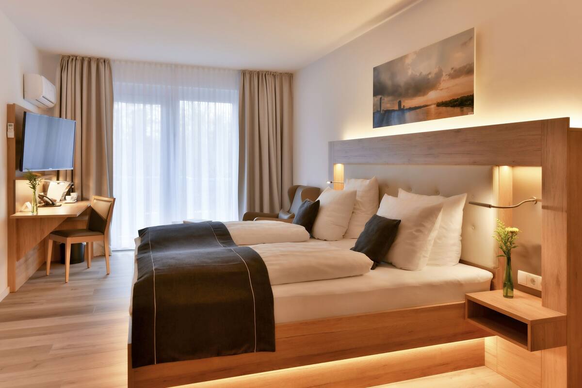 Une chambre d’hôtel avec un lit, un bureau, une chaise, une télévision et un tableau au mur.